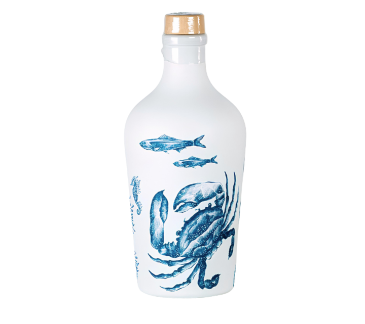 A white glass bottle with a gold cap, decorated with blue illustrations of a crab and fish, on a plain white background.