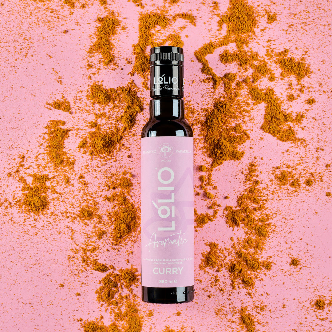 A bottle of Lolio Curry Aromatic Olive Oil with a pink label and black cap, centered on a pink background scattered with curry powder.