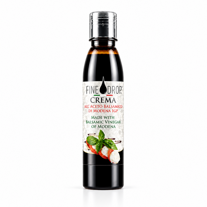 A bottle of Fine Drop Crema Balsamic Vinegar of Modena, featuring a dark glass bottle with a silver cap and a white label with red and green text and food illustrations, set against a plain white background.