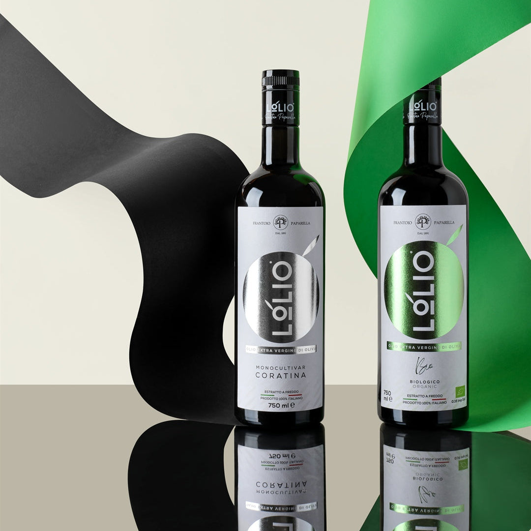 Two bottles of Lolio olive oil on a reflective black surface, styled with abstract black and green ribbon shapes against a light beige background.