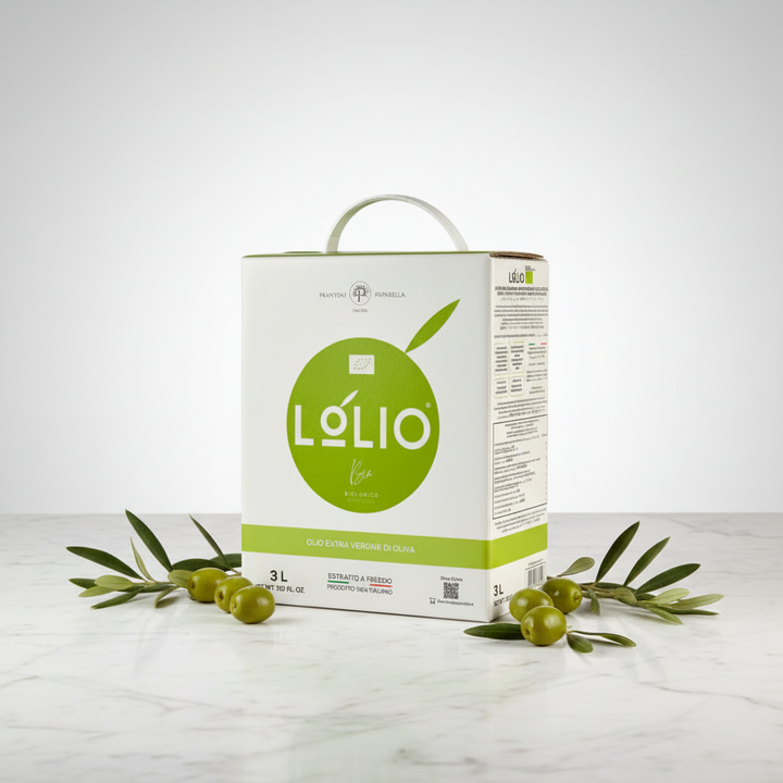 A 3-liter carton of Lolio extra virgin olive oil stands on a light marble surface with olive branches and green olives arranged around it. The carton is white with a large green oval logo and a white carry handle, photographed against a clean light gray studio background.