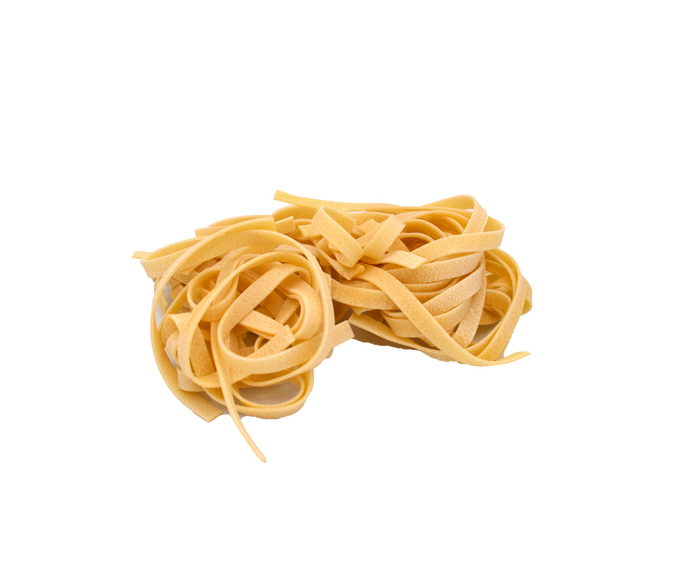 A small pile of uncooked flat pasta strands tagliatelle, in a light golden-yellow color, isolated on a solid white background.